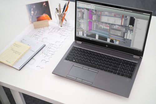 Laptop aufgeklappt auf Schreibtisch mit Utensilien